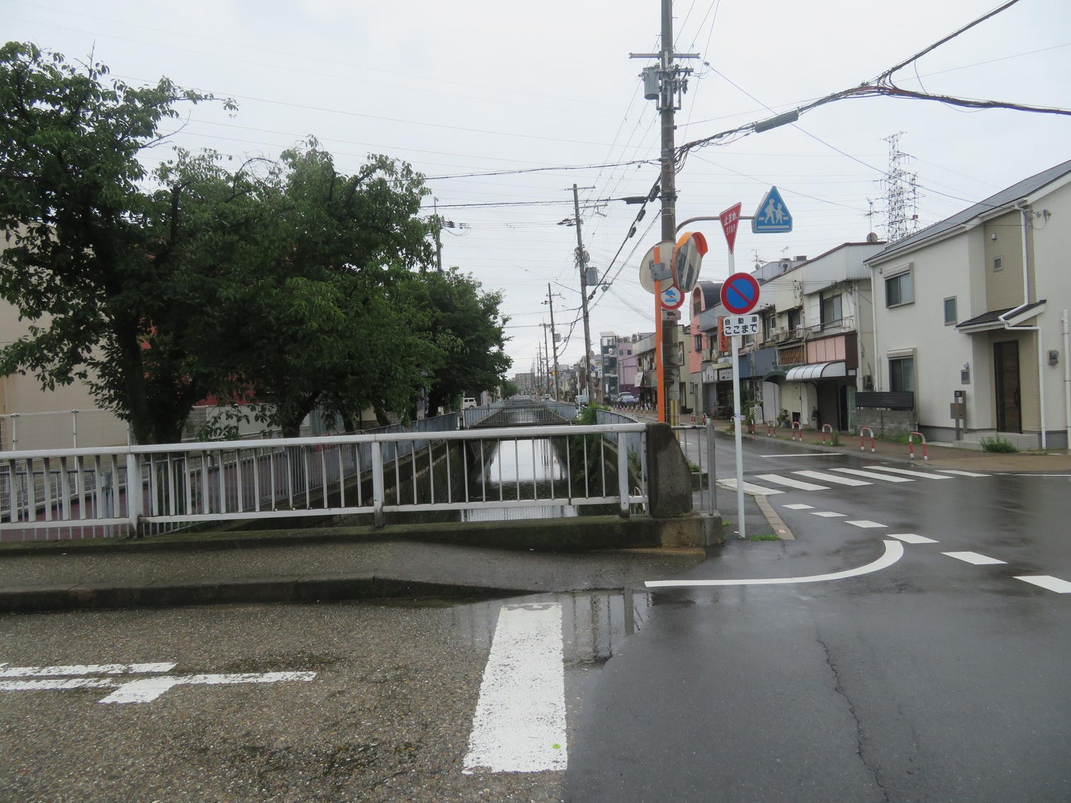 雨に濡れた高槻市春日町の水路沿いの街並み