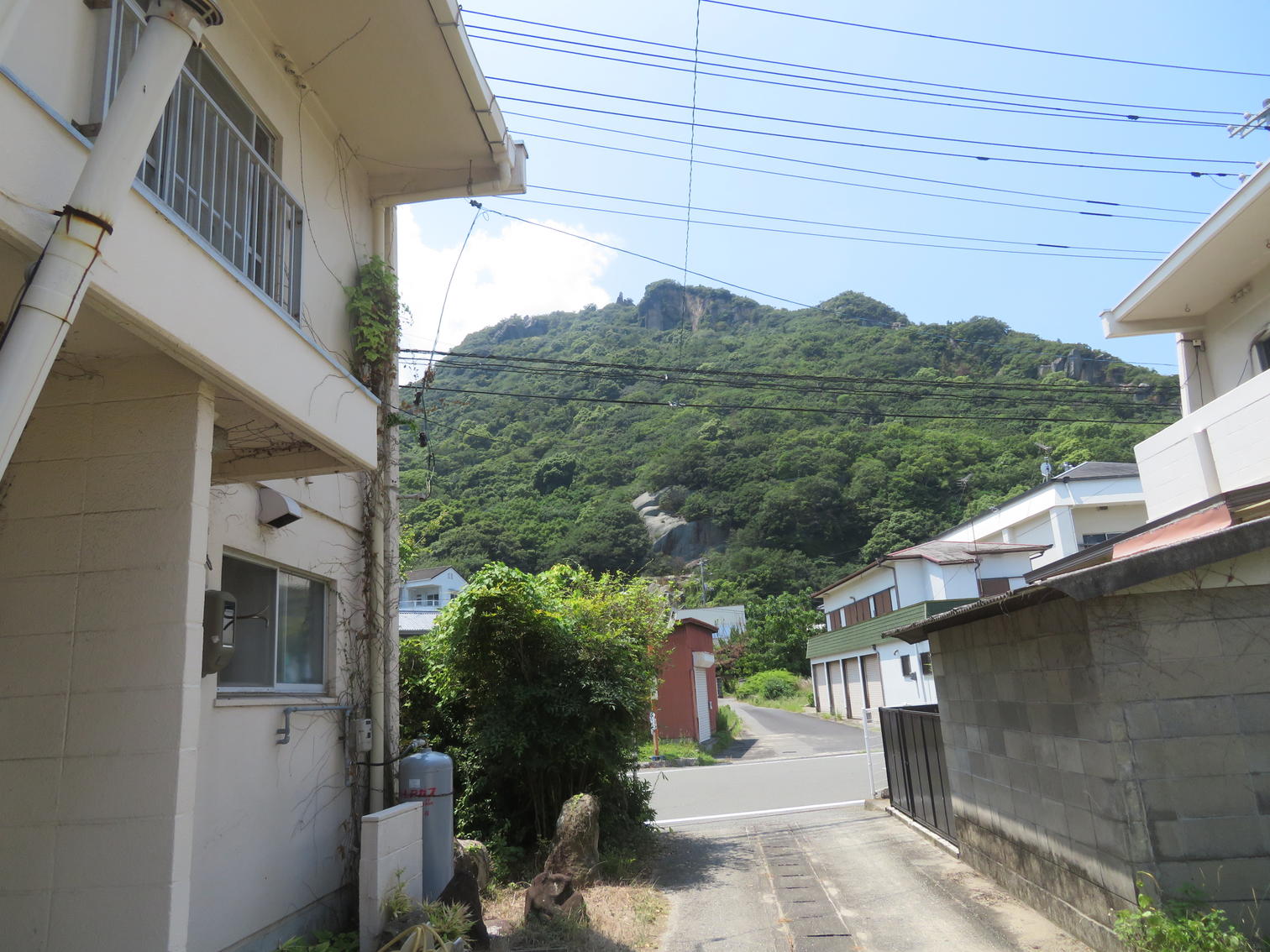 住宅の間の路地の先に見える岩肌の露出した山