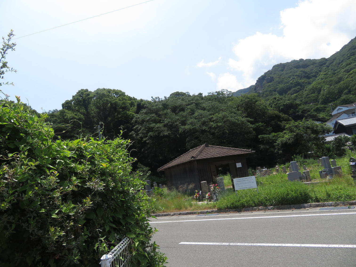 県道沿いの墓地の遠景と木造の堂