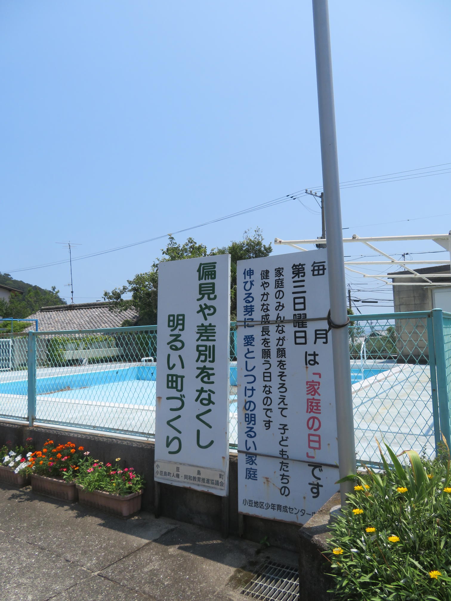 プール脇に立つ人権啓発と家庭の日の看板