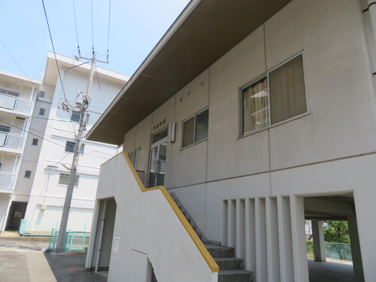 低層棟の外階段と奥に立つ町営住宅