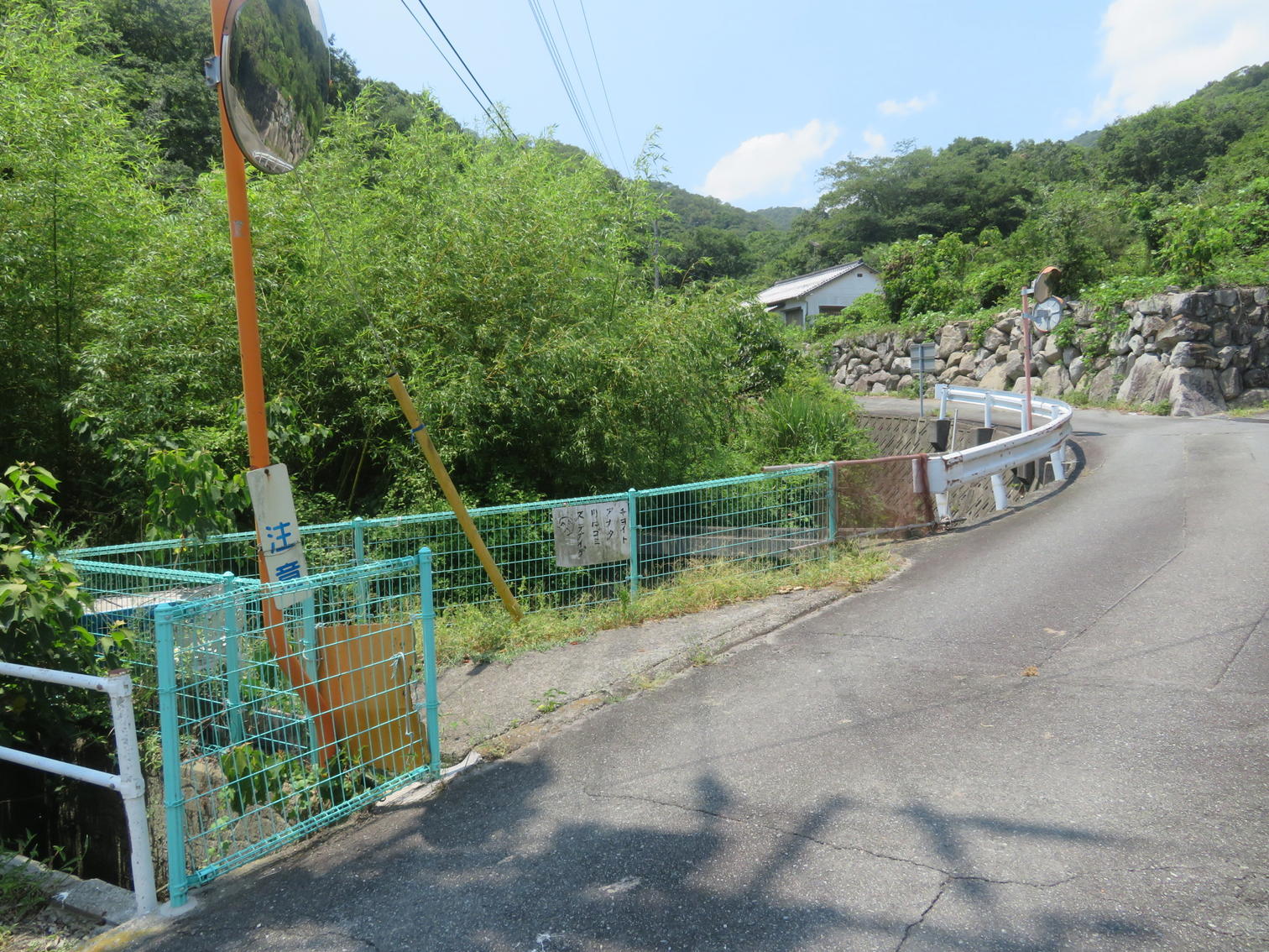 緑色のフェンス脇を曲がって上る急な道