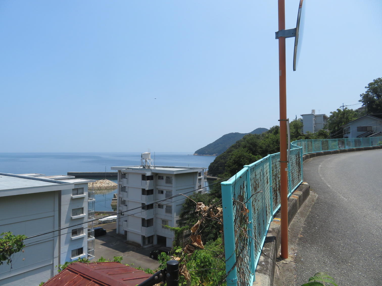 高台のカーブした道から見下ろす住宅と海
