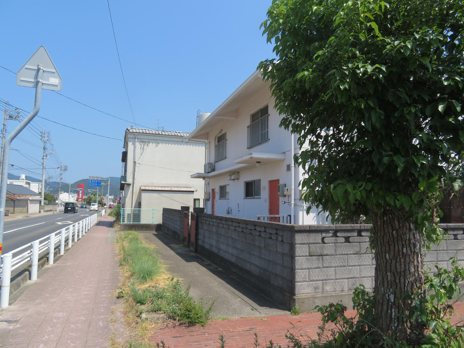 ブロック塀と樹木に囲まれた2階建て住宅