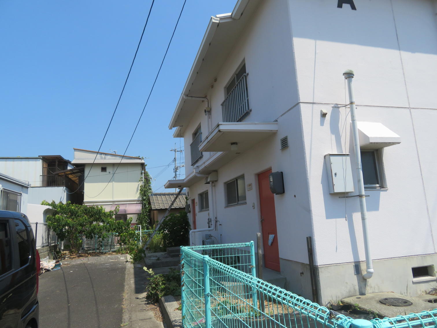 壁にAの記号が書かれた白い2階建て住宅