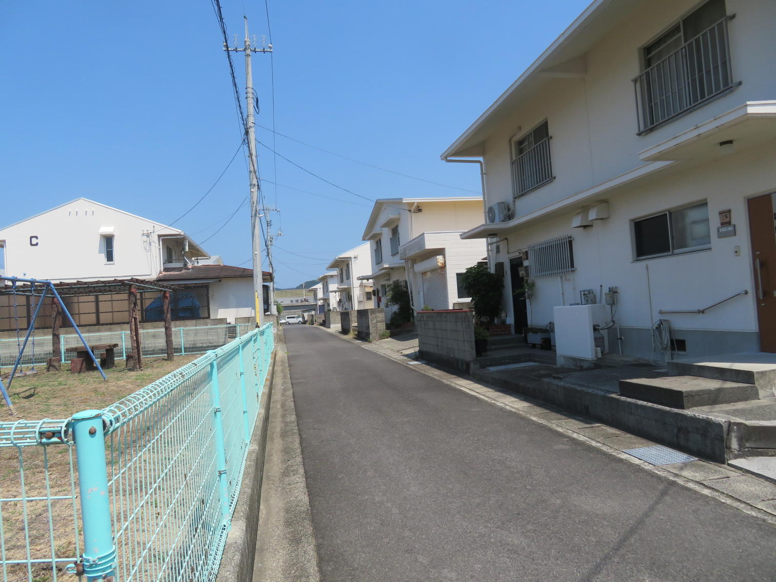 公園のフェンスとC棟の見える通り
