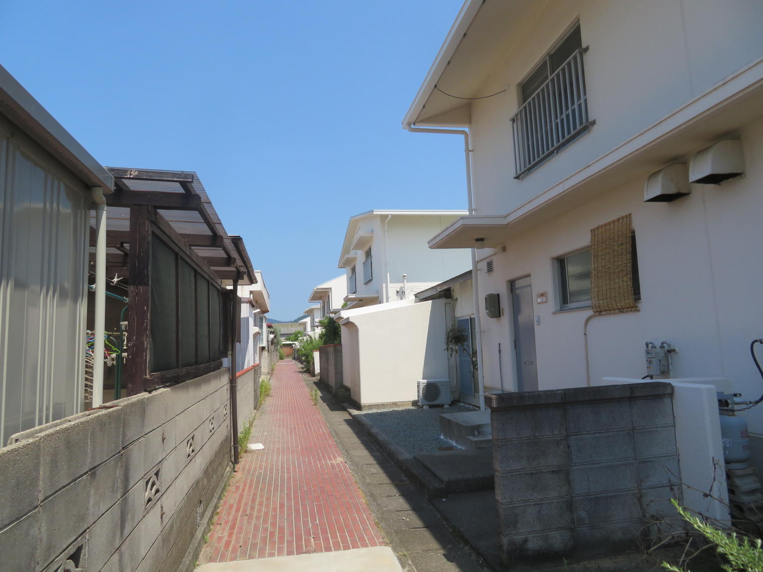 白い2階建て住宅の間を抜ける路地