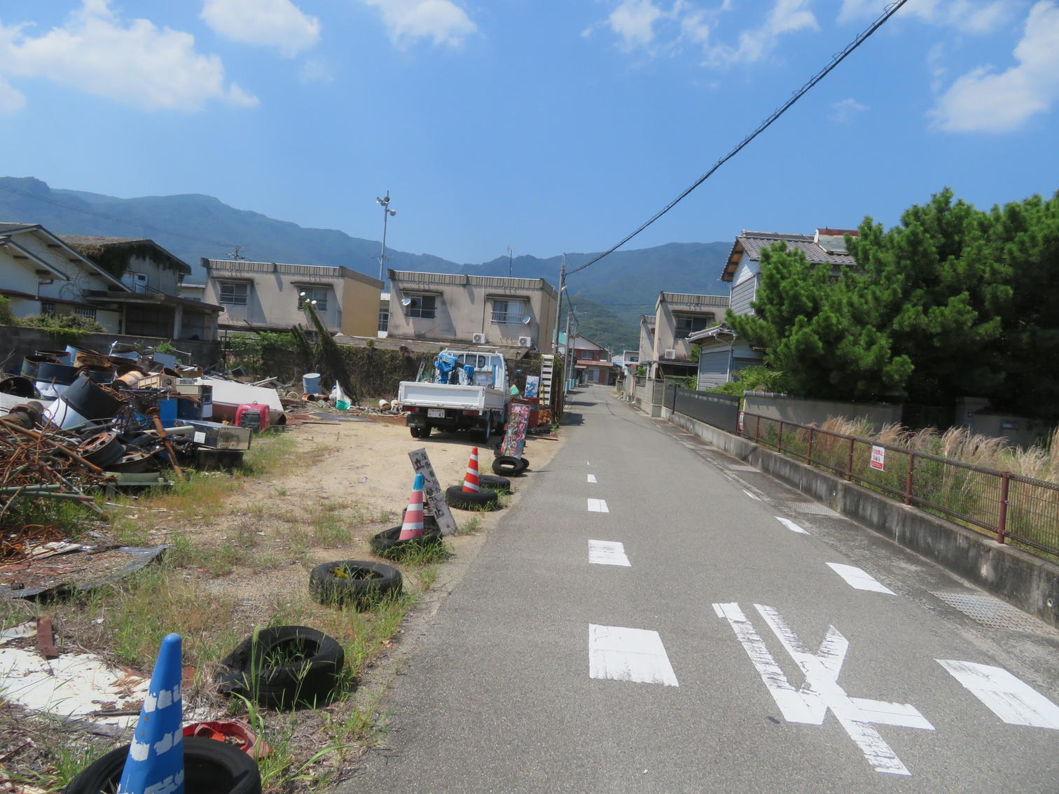資材の積まれた空き地と住宅地の道路