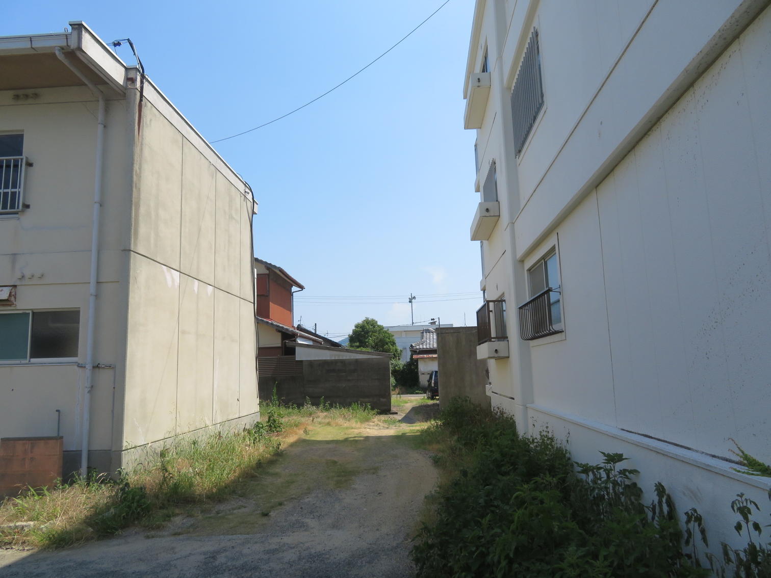 2階建て住宅の間の未舗装の空き地