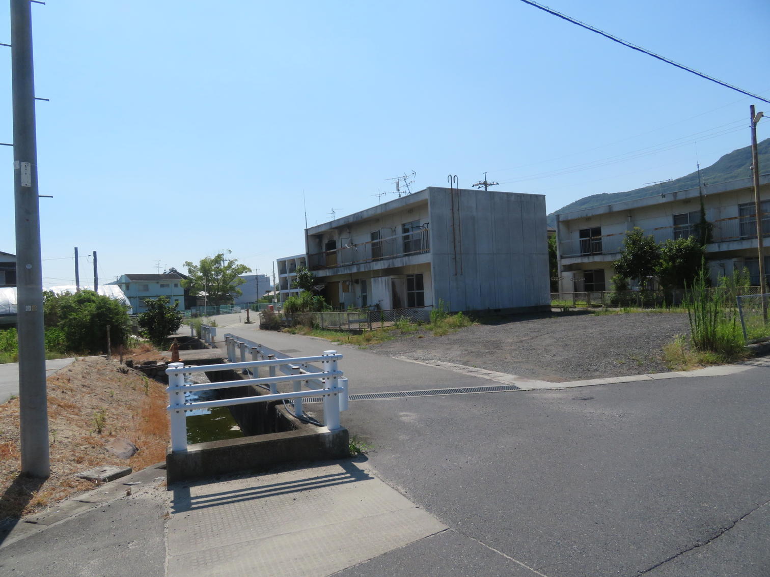 水路沿いの道と白い住宅。