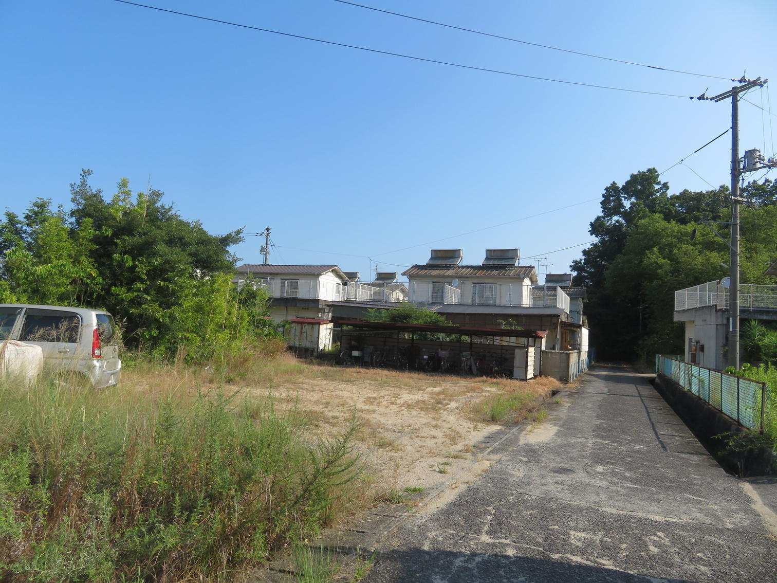 更地と駐車場の先に住宅が建つ。