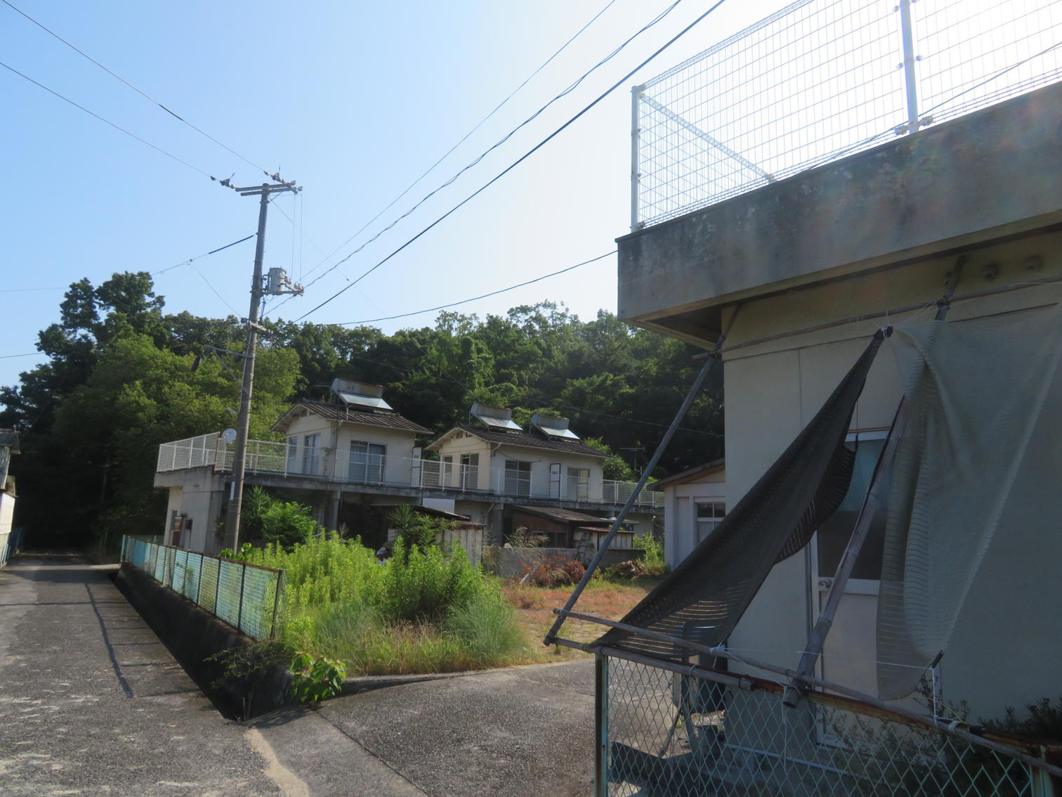 黒い日よけを張った家。奥に2階建ての住宅が続く。