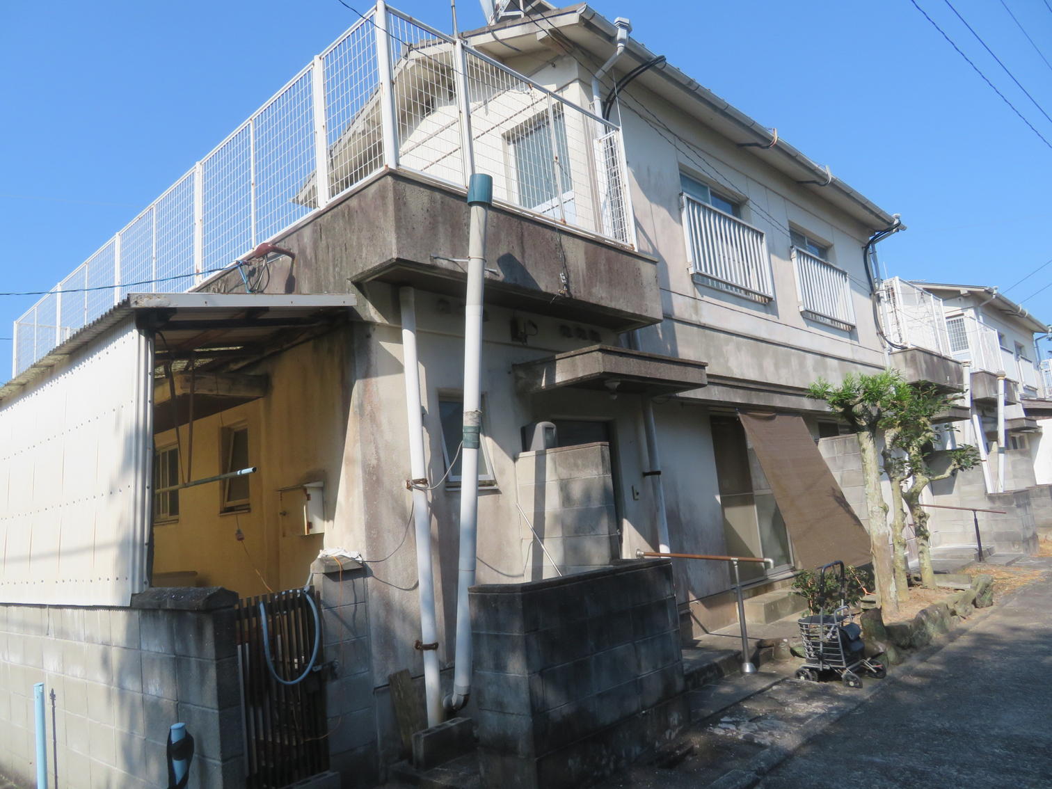 住宅地の脇で動く重機と、積まれた土砂。