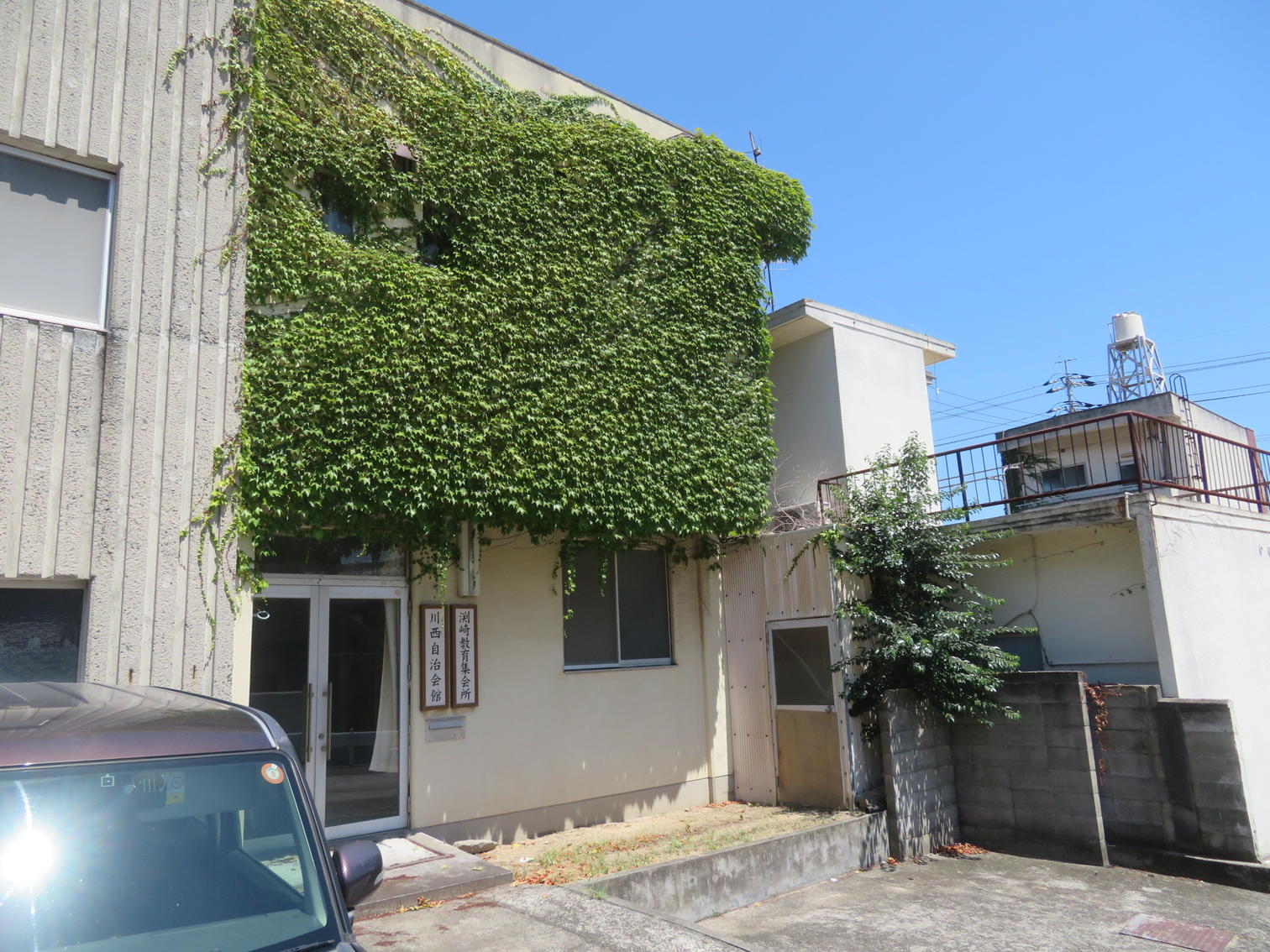 つたに覆われた2階建ての川西自治会館。