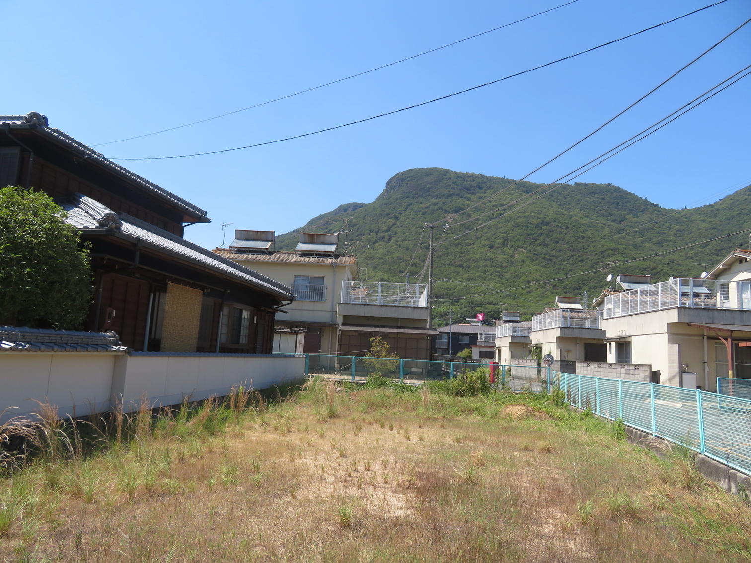 川を渡った先に、屋根に太陽熱温水器を載せた2階建てが並ぶ。