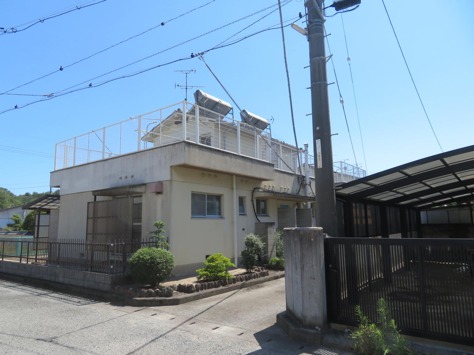 屋上に手すりを回し、太陽熱温水器を載せた2戸1棟の住宅。