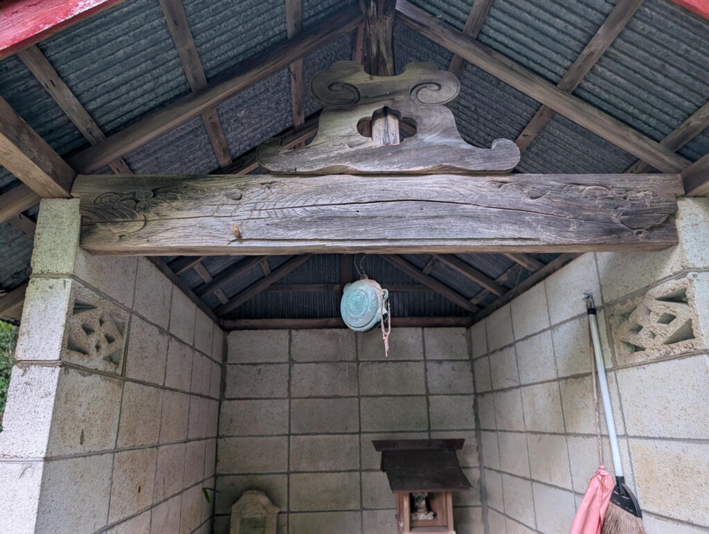 ブロック積みの祠。軒に鰐口が下がっている。